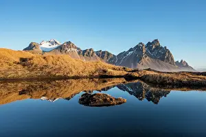 Overgrown: Mountains are reflected in a small lake, overgrown