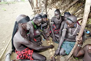 Mursi: Mursi tribe - boy sitting playing African game