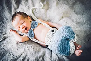 Sleep: A newborn baby boy sleeping in blue and grey knitted b