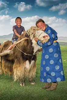 Embrace: Nomadic woman hugging the head of yak, a boy sitting