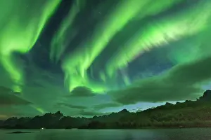 Situation: Northern lights over the fjord, behind them rugged