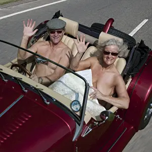 Model: NUDE older couple driving in an open top sports car