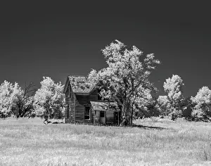Infrared: Old deserted farm house with plow