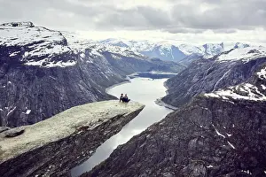 Platform: Paar sits on a rock platform on Trolltunga and looks