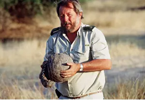 Held: PANGOLIN - Curled in ball for defence, held by man