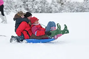 Sledging: Parents and children sledging in deep snow on slopes