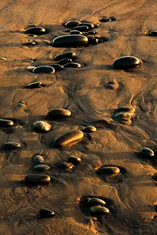 Adam: Pattern of smooth round stones on beach at sunset