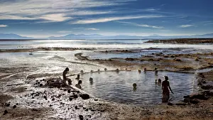 Persons: People bathe in hot springs with views of mountains and vast skies