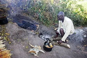 Cooked: People - man cooking, with fish being cooked over fire