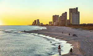 Housing: People walking and playing on the beach as the sun sets over the Gulf of Mexico at Gulf Shores