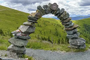 Persons: A person sits on a bench with a view of mountainous landscape and cloudy sky