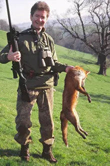 Holds: Pest control: rifleman holds dead fox