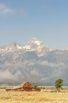 Infront: Pioneers barn in landscape infront of the Grand Teton Range