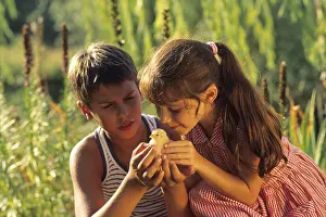 Fledging: Portrait of two children tenderly watching a fledging