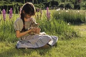 Crossbreed: Portrait of a young girl with a kitten in the garden