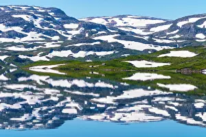 Fell: Reflection of partly snow-covered mountains in Lake