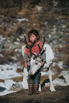 Nomadic: Reindeer herder girl with baby reindeer. Ulaan taiga