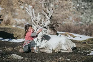 Nomadic: Reindeer herder girl with baby reindeer. Ulaan taiga