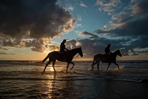 Pace: Riders and horses in water at dusk
