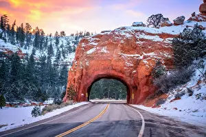 Highway: Road with tunnel through red rock arch in snow