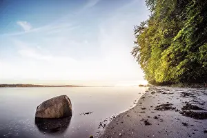 Steep: Rock in the calm water on a nordic beach with gr