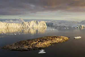 Midnight: rocky island and large icebergs at midnight