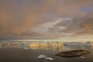 Midnight: rocky island and large icebergs at midnight