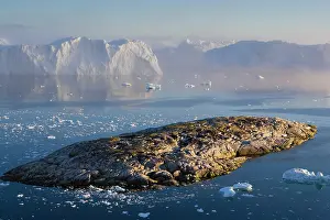 Midnight: Rocky island and large icebergs at midnight