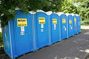 Toilets: Row of blue Portaloos installed on pavement outside