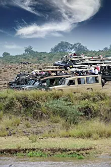 Cars: Safari cars on the Mara River with tourists waiting