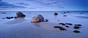Blur: Sandy beach beach with large boulders and seaweed