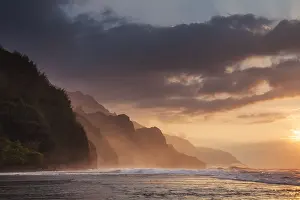 Kauai: The setting sun lights up the rugged cliff of t