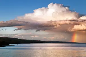 Accompanied: Shoreline with approaching rainclouds accompanied by a rainb