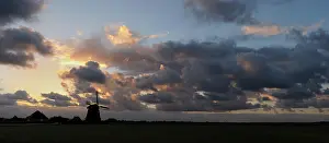 Petten: Silhouette of a Dutch windmill against a cloudy sky