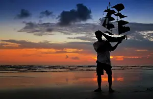 Models: Silhouette of a man holding a kite shaped like a