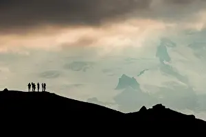 Balancing: Silhouette of tourists at the ridge with view of