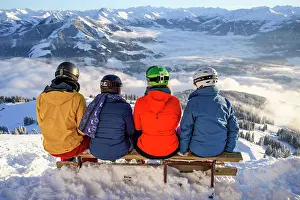 Skiing: Skiers sitting on a bench and looking down on snow-covered