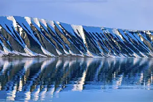 Mayen: Snow capped mountain by a fjord with water refle
