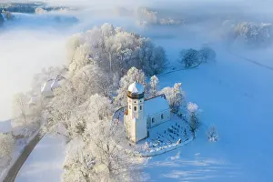 Foothills: Snow-covered church St. Johann Baptist. Fog mood