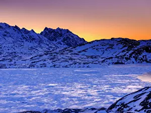 Daybreak: Snowy mountains above the frozen Kong Oscar Fjord at dawn