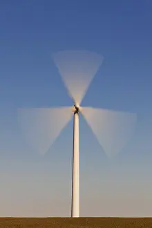 Wind: Spinning blades of windturbine in field against blue sky