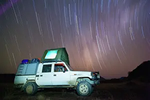Tent: Star trails encircle a tourist vehicle in the southern hemis