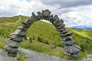 Hills: Stone arch on a hiking trail with a view of green hills and cloudy sky