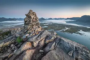 Cairn: Stone pyramid at the top of Hoven at dusk, mountains