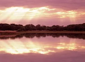 Beams: Sun beams breaking through clouds at a lake with reflection