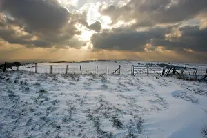 Bursting: Sun bursting through clouds over a snowy landscape
