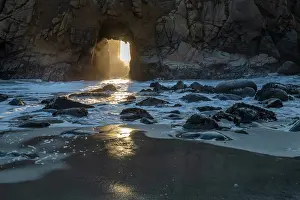 Betty: Sun shines through a tunnel in a sea cliff in the