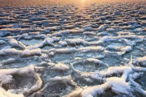 Uitgeestermeer: Sunrise at frozen lake with sun reflecting on ice floe and snow