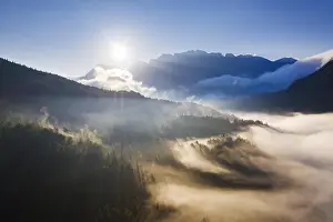 Karwendel: Sunrise, sunbeams in fog over forest at Ferchensee