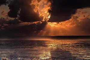 Sunrays: Sunset on the Waddensea with enormous clouds and sunrays at